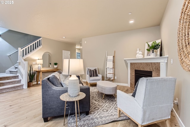 living area with a tiled fireplace, wood finished floors, recessed lighting, stairway, and baseboards