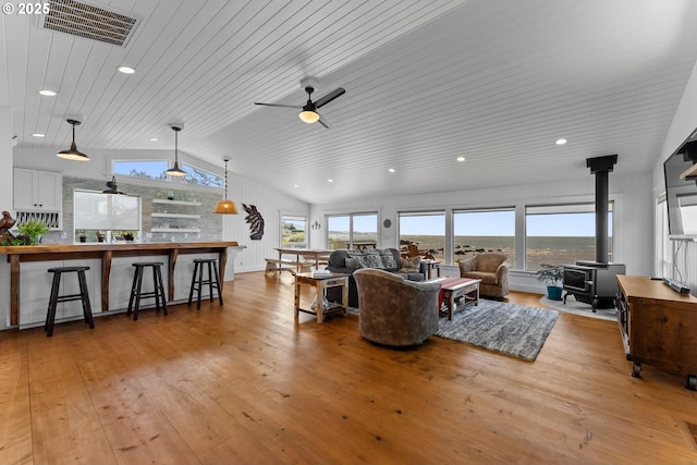 15436 Oceanview Dr, Brookings, OR 97415 - living room with light wood finished floors, ceiling fan, visible vents, vaulted ceiling, and a wood stove