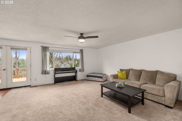 carpeted living room featuring french doors, ceiling fan, and a textured ceiling