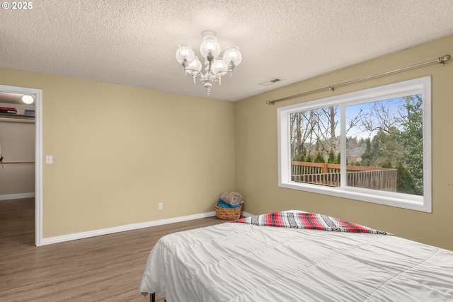 bedroom with hardwood / wood-style flooring, a textured ceiling, and a chandelier