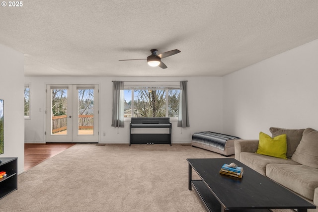 living room featuring light carpet, a textured ceiling, and ceiling fan