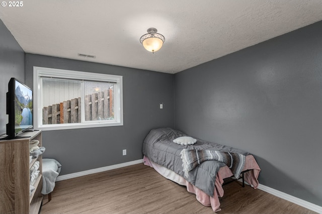 bedroom featuring hardwood / wood-style flooring and a textured ceiling