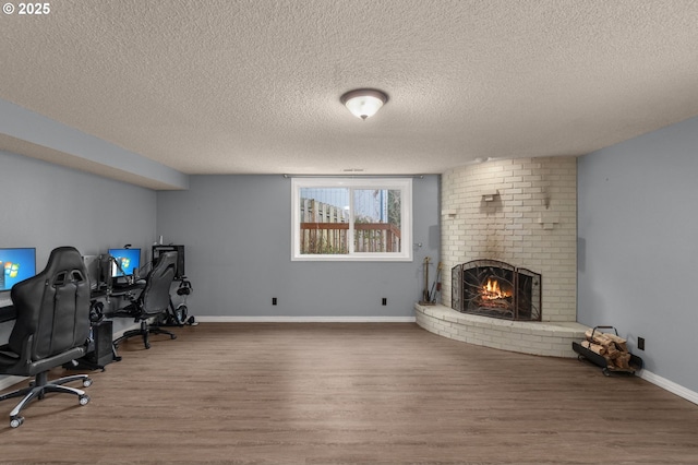 office area featuring wood-type flooring, a fireplace, and a textured ceiling