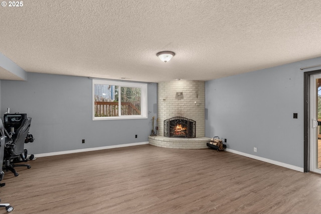 unfurnished living room with a brick fireplace, wood-type flooring, and a textured ceiling