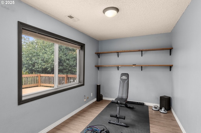 exercise room featuring a textured ceiling and light wood-type flooring