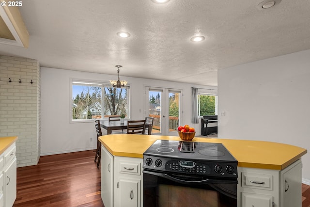 kitchen featuring dark wood-type flooring, electric range, white cabinets, decorative light fixtures, and french doors