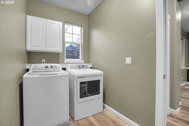 laundry area featuring light hardwood / wood-style floors, cabinets, and washing machine and dryer