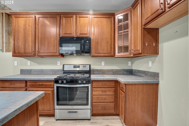 kitchen with stainless steel range with gas cooktop and light hardwood / wood-style floors