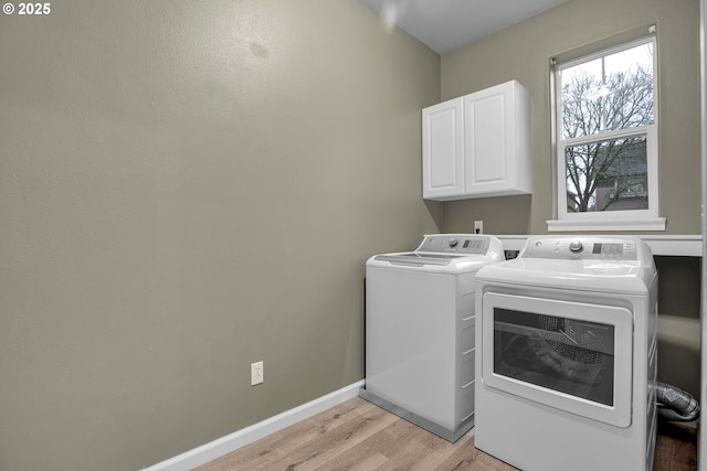 laundry area featuring cabinets, light hardwood / wood-style flooring, and washing machine and clothes dryer