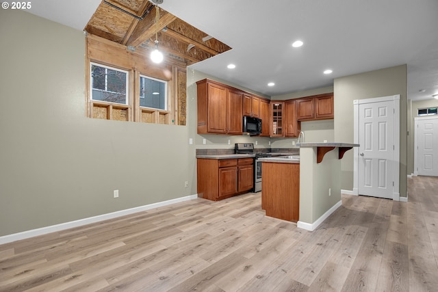 kitchen featuring stainless steel range oven, light wood-type flooring, and a breakfast bar area