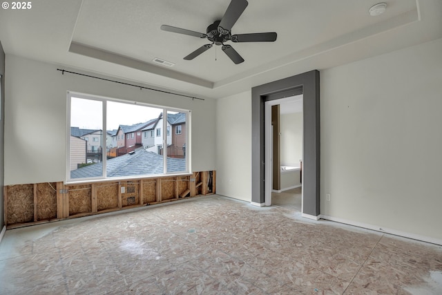 spare room with ceiling fan and a tray ceiling