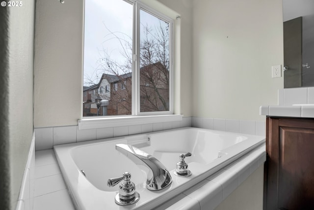 bathroom featuring tiled tub and vanity