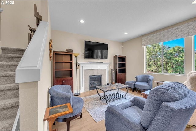 living room with wood finished floors, recessed lighting, stairs, and a fireplace