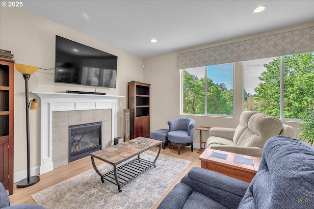 living area with wood finished floors, recessed lighting, stairway, and a tile fireplace