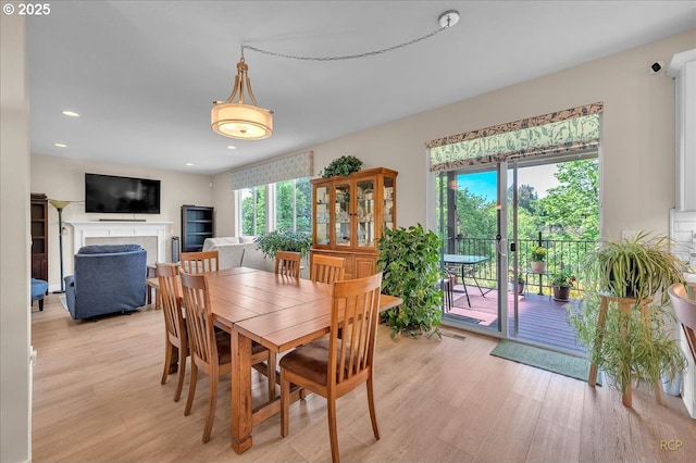 dining room featuring light wood-style floors, a fireplace, and recessed lighting
