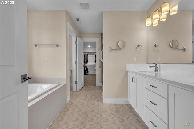 full bathroom with tile patterned floors, baseboards, vanity, a bath, and a spacious closet