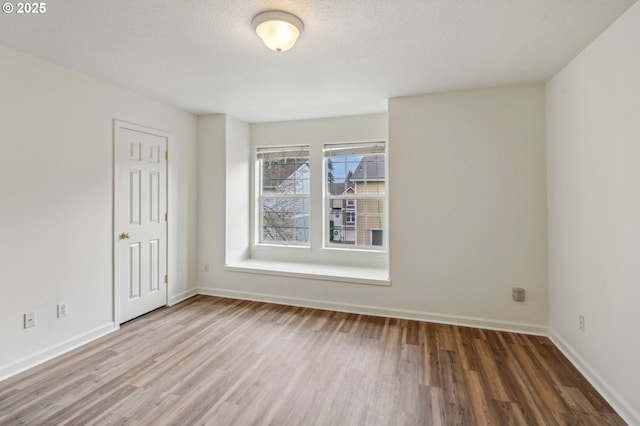 spare room featuring baseboards and wood finished floors