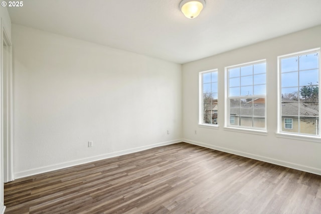 empty room with baseboards and dark wood-style floors