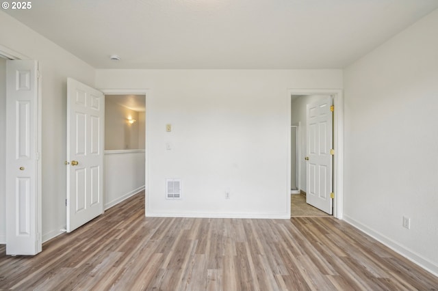 unfurnished bedroom featuring baseboards, visible vents, and light wood-style flooring