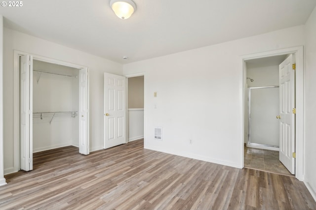 unfurnished bedroom featuring baseboards, visible vents, light wood-style flooring, and a closet
