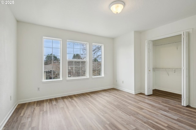 unfurnished bedroom with baseboards, wood finished floors, and a closet