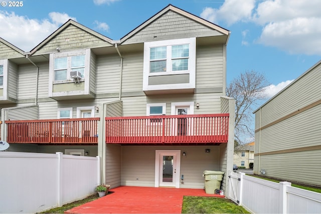 rear view of property with fence private yard, a balcony, and a deck
