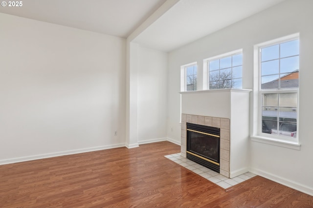 unfurnished living room with baseboards, wood finished floors, and a fireplace