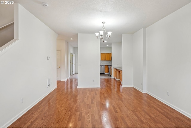 unfurnished dining area featuring visible vents, light wood finished floors, baseboards, and a notable chandelier