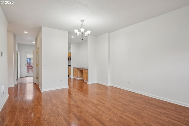 unfurnished dining area featuring an inviting chandelier, recessed lighting, baseboards, and light wood-type flooring
