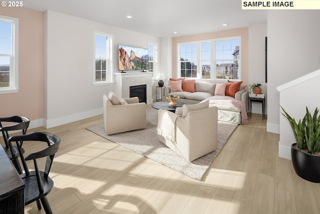 living room featuring light wood-type flooring and a tiled fireplace