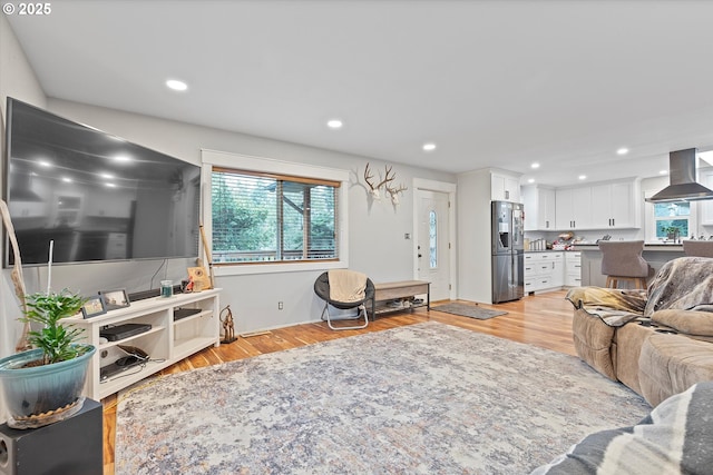 living area with light wood-style floors, plenty of natural light, and recessed lighting