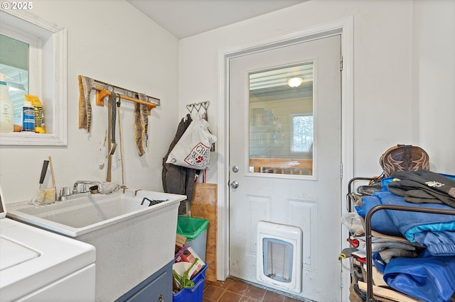 clothes washing area with laundry area, dark tile patterned floors, and a sink