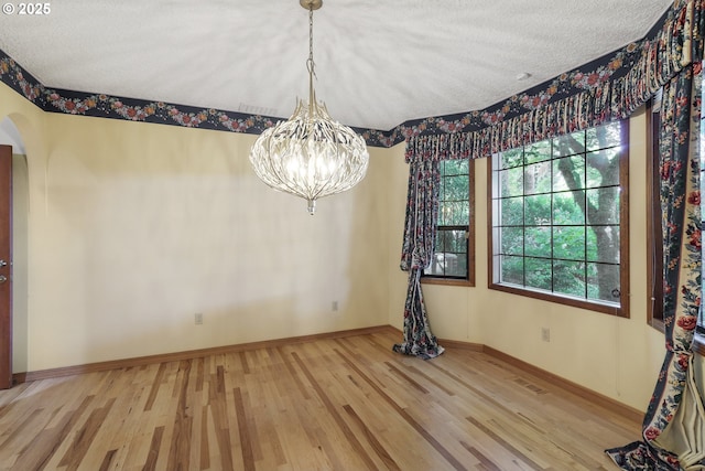 17002 NE 50th Ave, Vancouver, WA 98686 - unfurnished dining area featuring wood finished floors, a chandelier, baseboards, a textured ceiling, and arched walkways