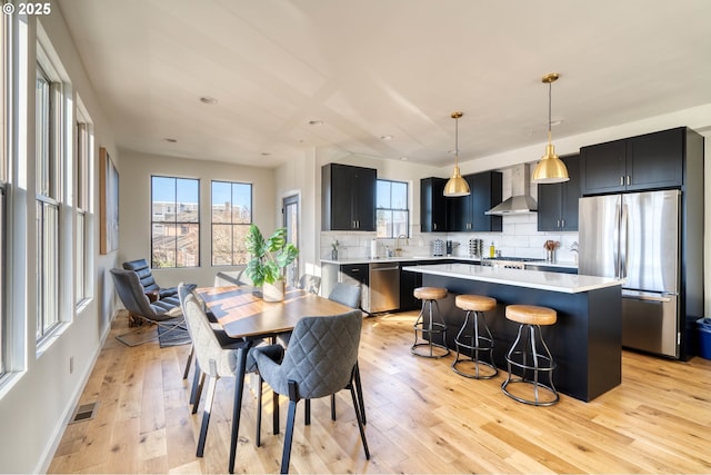 dining room with light wood-style floors, visible vents, and baseboards