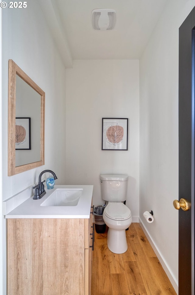 bathroom with toilet, wood finished floors, vanity, and baseboards