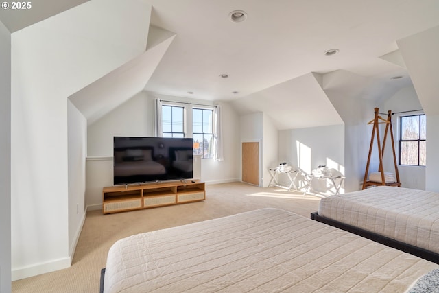 bedroom featuring lofted ceiling, multiple windows, and light colored carpet