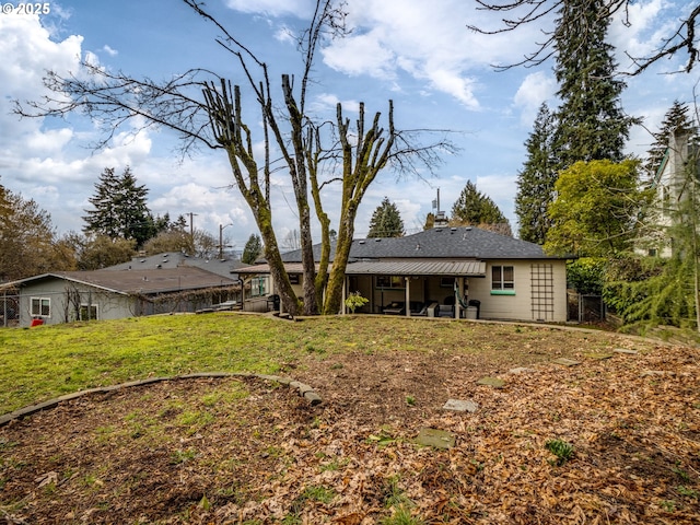 rear view of house featuring a yard and fence