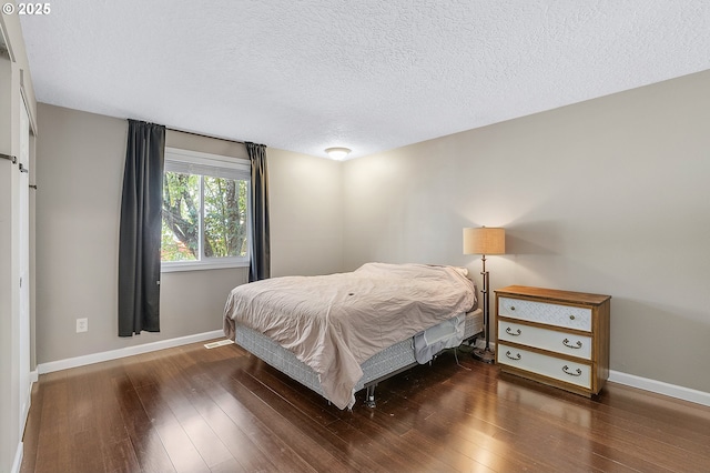 bedroom with baseboards, wood-type flooring, and a textured ceiling