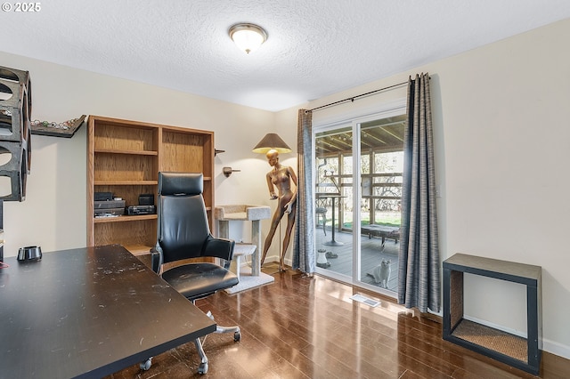 office space with dark wood finished floors, baseboards, visible vents, and a textured ceiling