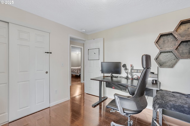 office with baseboards, a textured ceiling, and wood finished floors