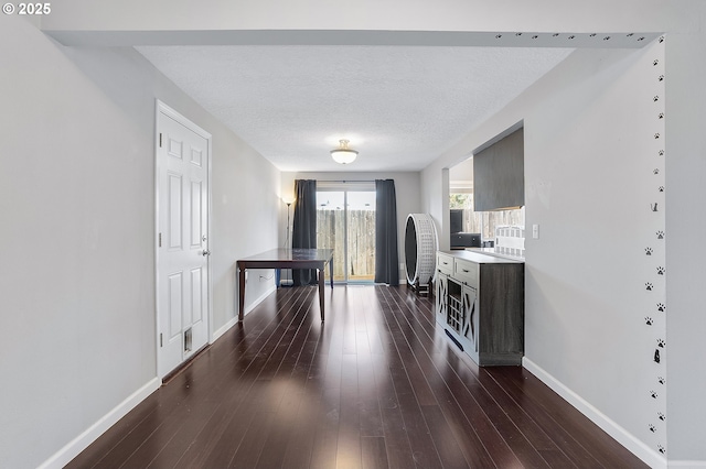 interior space featuring baseboards, a textured ceiling, and dark wood-style flooring