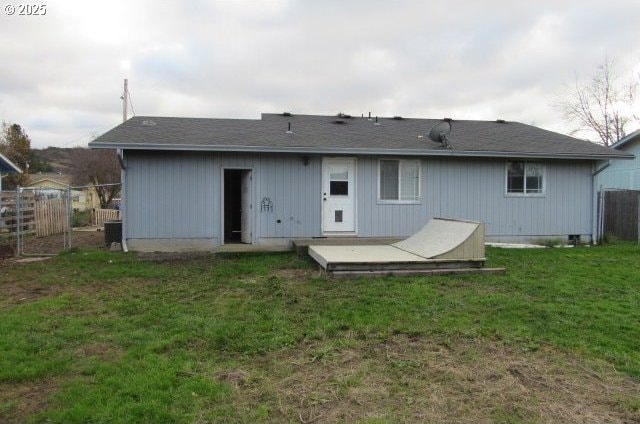 rear view of property featuring a lawn and central air condition unit