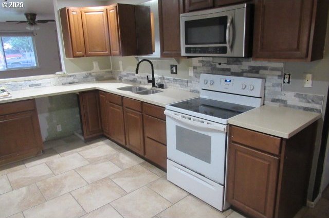 kitchen with light tile patterned flooring, ceiling fan, sink, and white range with electric stovetop