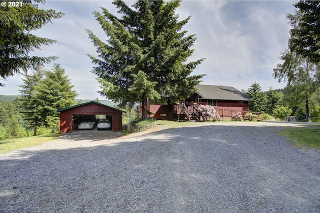 view of front of home with a wooden deck, a detached carport, an outdoor structure, and driveway