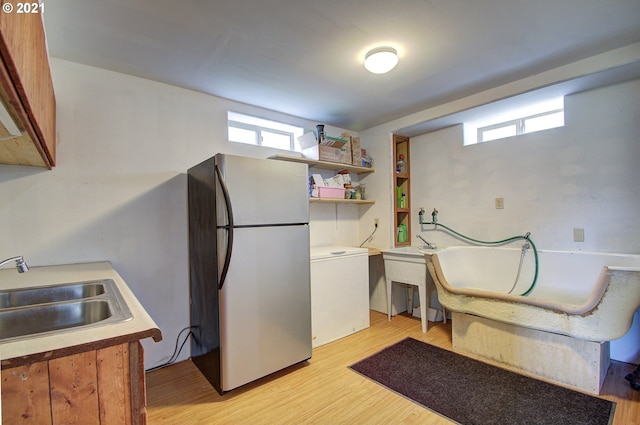 kitchen featuring light wood-style flooring, a sink, freestanding refrigerator, fridge, and light countertops