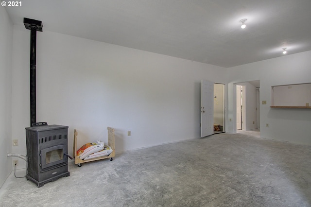 unfurnished living room featuring a wood stove and concrete floors