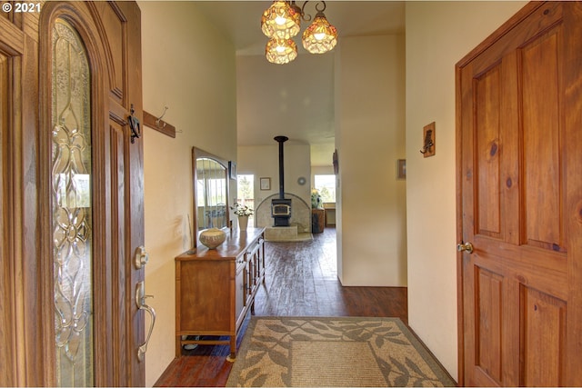 entrance foyer featuring dark wood finished floors, a wood stove, and a chandelier