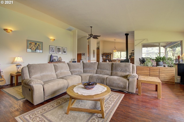 living area with lofted ceiling, a wood stove, a ceiling fan, and dark wood-style flooring