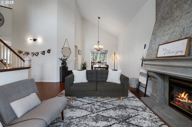 living room with an inviting chandelier, a large fireplace, high vaulted ceiling, and dark hardwood / wood-style floors