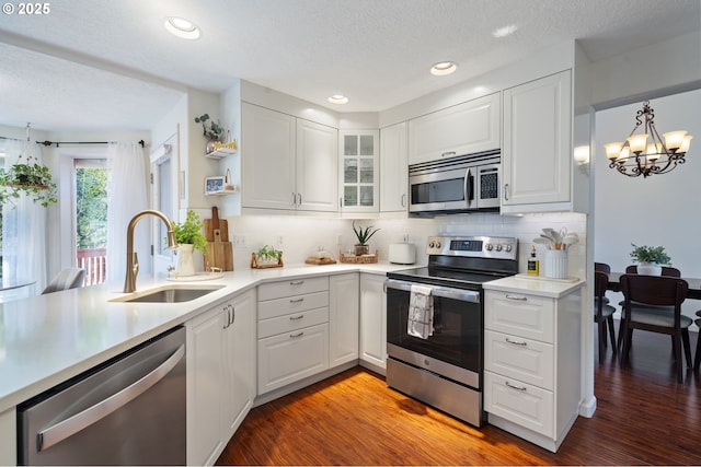 kitchen with white cabinetry, stainless steel appliances, sink, and a notable chandelier